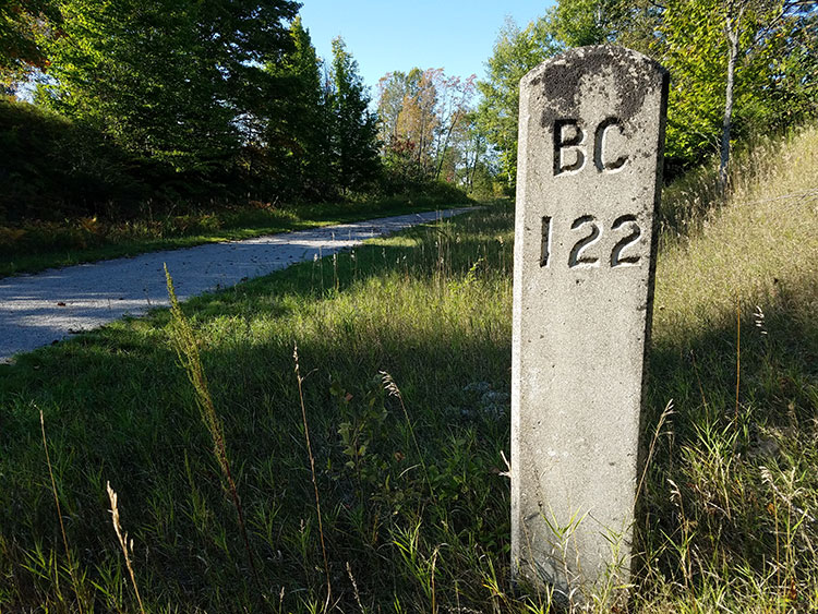 Original railroad mile marker on the North Central State Trail, just north of Gaylord. It told the engineer how many miles to Bay City. This image conveys the historic nature of Michigan’s rail trails. Credit: Dan Spegel