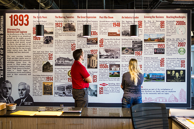 Spence Brothers Project Development Lead Wayne Hofmann and Route writer Chelsea Rowley look through the company's history at their headquarters in Saginaw