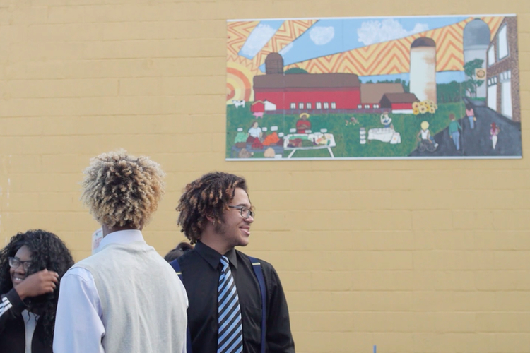 Ypsilanti Community High School students stand by their mural at the Ypsilanti Farmers Market downtown.