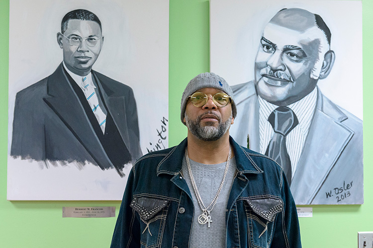 Bryan Foley stands in front of paintings by Washington Lee Osler at the Parkridge Community Center