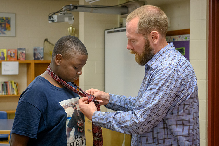 Mosaic Church of Ann Arbor pastor Shannon Nielsen (R) helps a student at Erickson Elementary learn how to tie a tie
