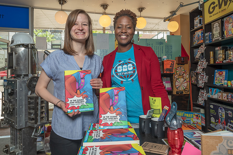 Megan Gilson and Naimah Wade with copies of In The Clounds Over Ypsilanti: Community Superhero Stories