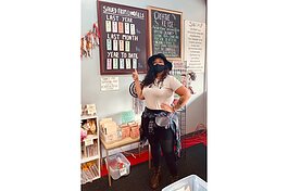 An employee at SCRAP Creative Reuse Ann Arbor points to a sign showing how much material the organization has diverted from landfills.