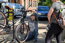 Anthony Lutz repairing a bike at the Ypsi Bike Co-op's booth at Ypsilanti's Depot Town farmers market.