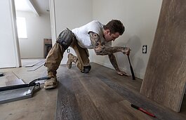 Gavin Witten, an Ypsilanti-based contractor, lays flooring during a recent remodel project at one of Yarrow's properties. Yarrow works only with local tradespeople.