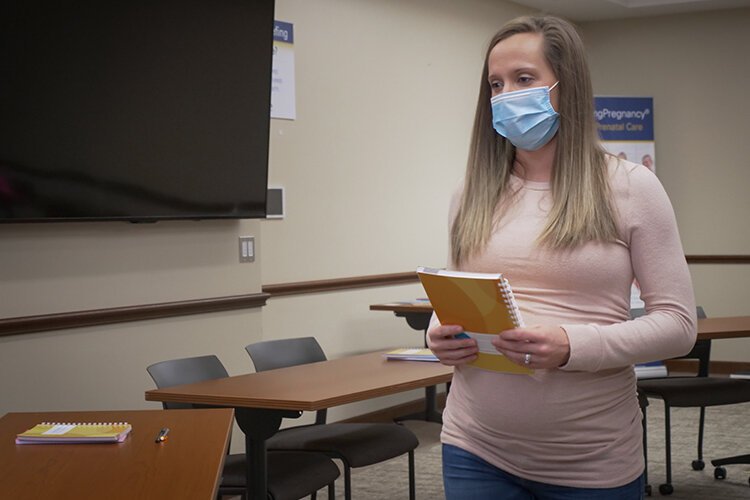 A pregnant patient carries her CenteringPregnancy booklet, which is part of the CenteringPregnancy program and is used for the patients to keep track of their vitals such as weight and blood pressure.