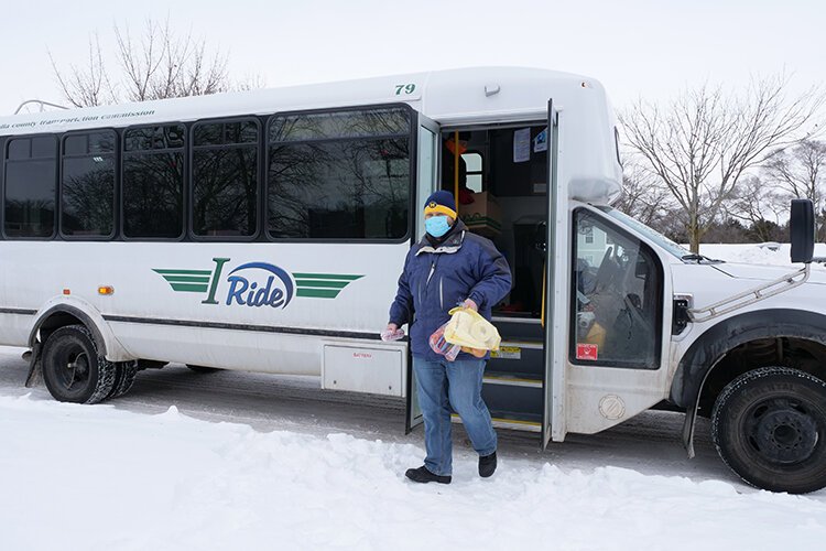 Marc Cooper, a volunteer, steps off an I-Ride bus to help deliver a package from The Care Store.