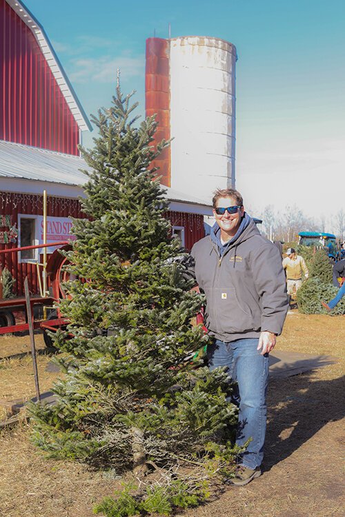 Mt. Pleasant resident Kent VanderLoon poses for a photo, showing off his freshly-cut Christmas tree for this year's holiday. 