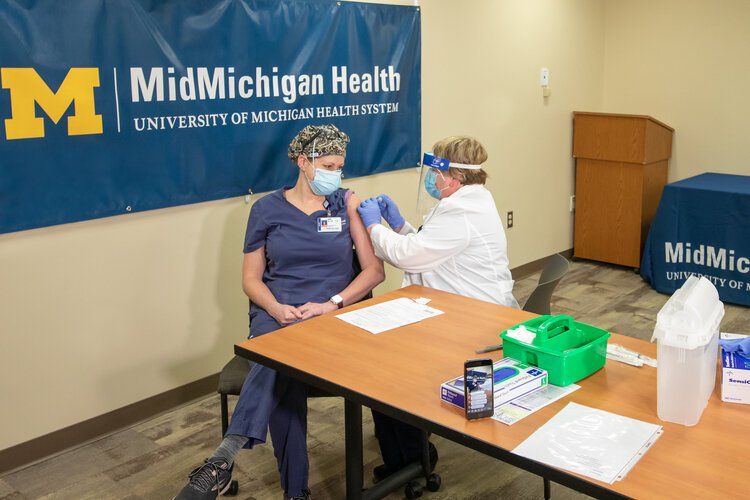 This week, the COVID-19 vaccine was delivered to MidMichigan Medical Center – Midland. Shortly after the vaccine was delivered Wednesday morning, the first dose was given to AJ Schafer, R.N., a medical ICU nurse, of Weidman, Michigan.