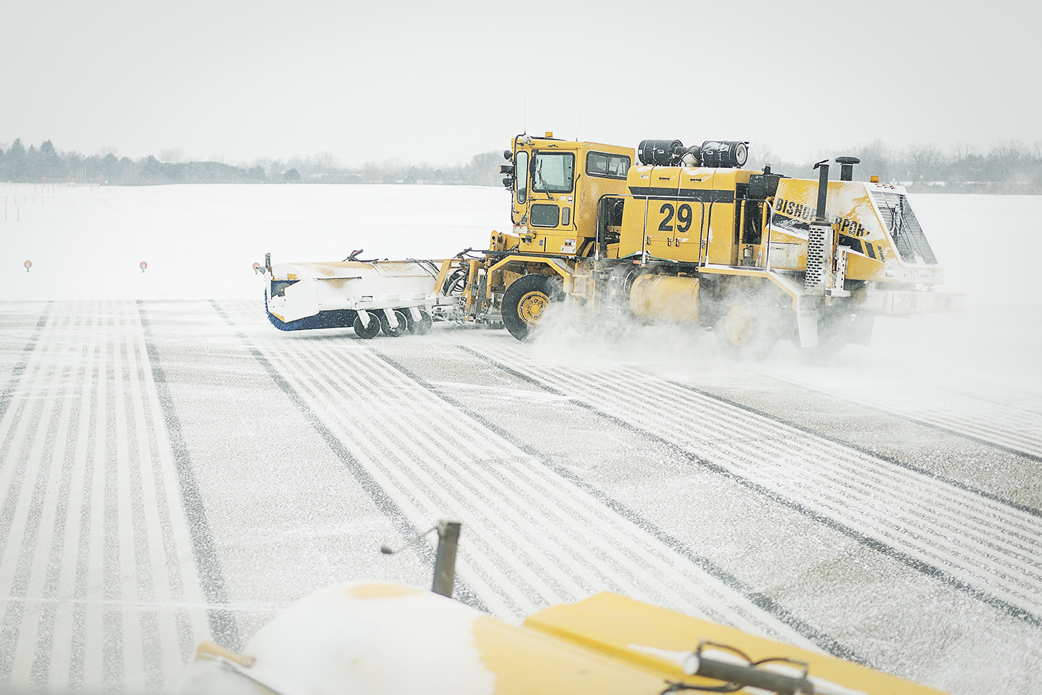 A broom truck, using massive brushes and a blower clears snow from the runway at Bishop International Airport.