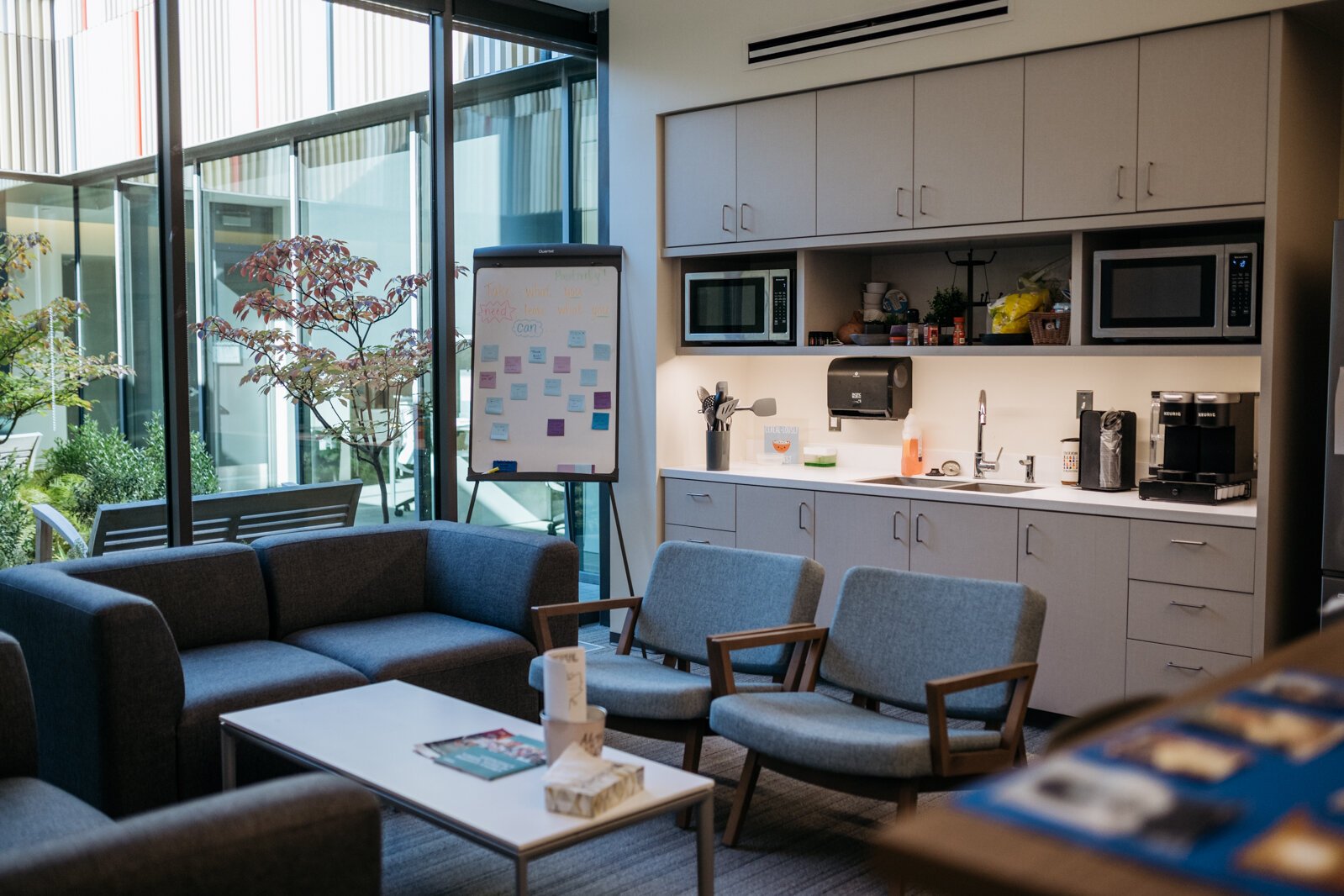 The staff wellness lounge sports healthy snacks, coffee, yoga on TV, and space for eating, relaxing, or finishing a project. The adjacent atrium encourages health and wellness among teachers.