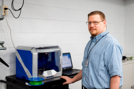 Mark Hancock next to the library's 3D printer