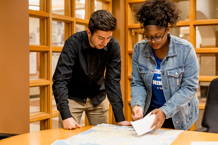 Momar Almadani and Yarnise Hines adding stickers to a map of Metro Detroit, indicating areas they have impacted through their studies.