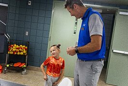 Jeff Rekeweg chats with Isabella Zielinski of Georgia, 7, a participant in a youth tennis camp.