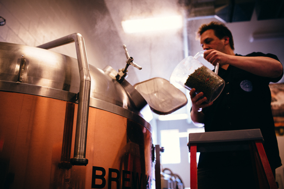 Brian Confer adds hops during the brewing process. 