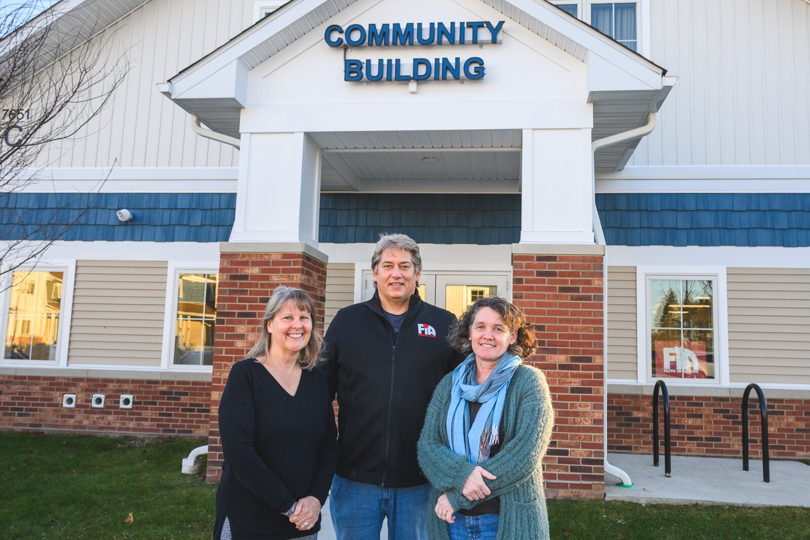 Sarah Shugart, Craig Rafail, and Wendy Carty-Saxon outside of the Hilltop View Apartments' community building.