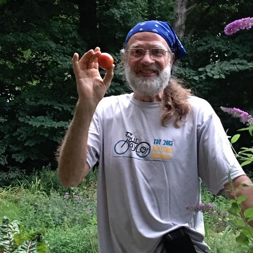 Tomme Maile proudly holds the garden’s first tomato of the season.