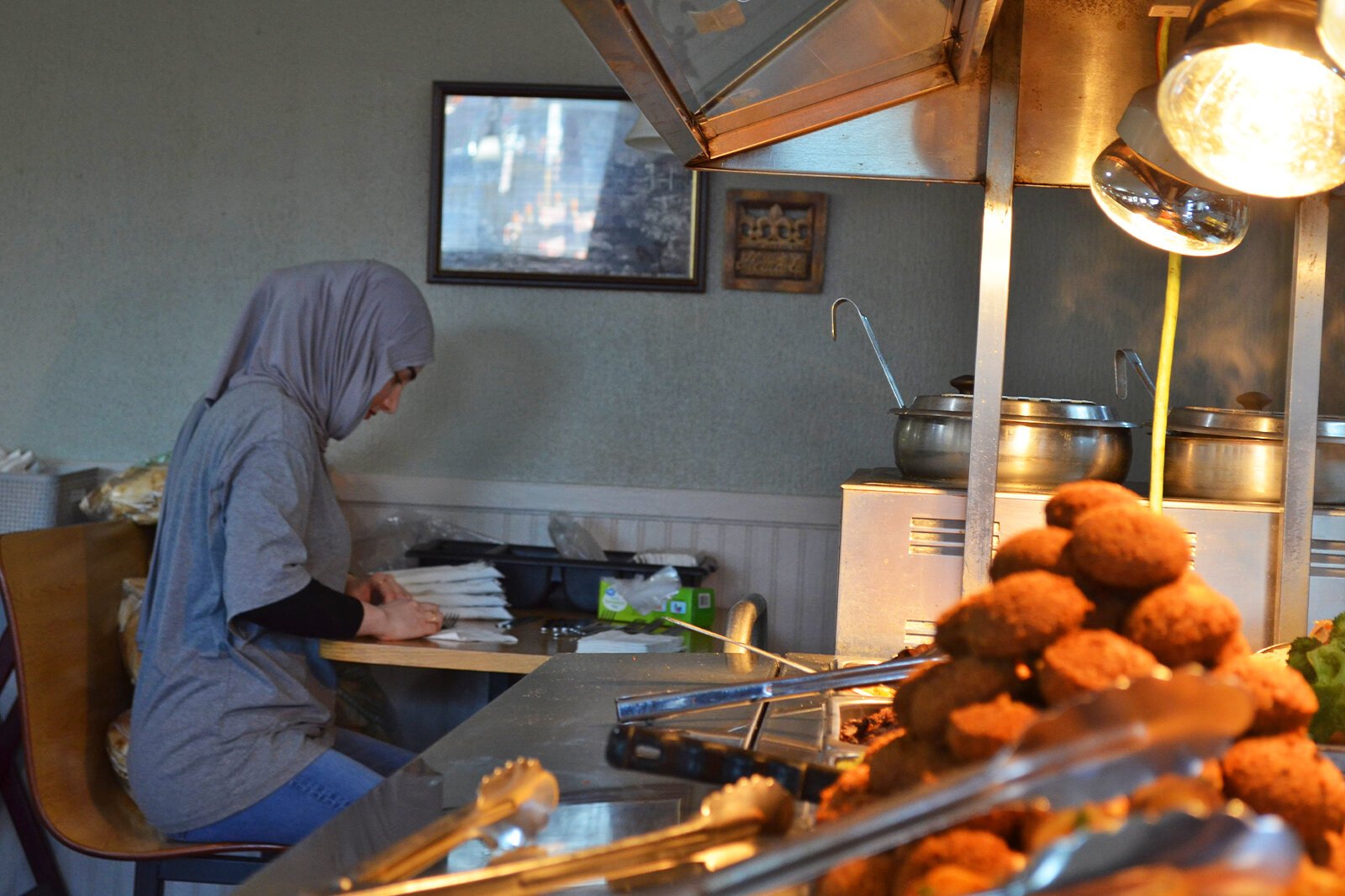 Shawarma King is a family-owned and operated business. One of the owners' daughters rolls silverware in preparation for the lunch rush.