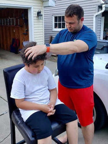 The COVID-19 shutdown meant at-home haircuts. Don Solesbee is shown cutting the hair of neighbor Rowin Hernandez,7. He also cut the hair of two other boys and two adult neighbors as well as his son.