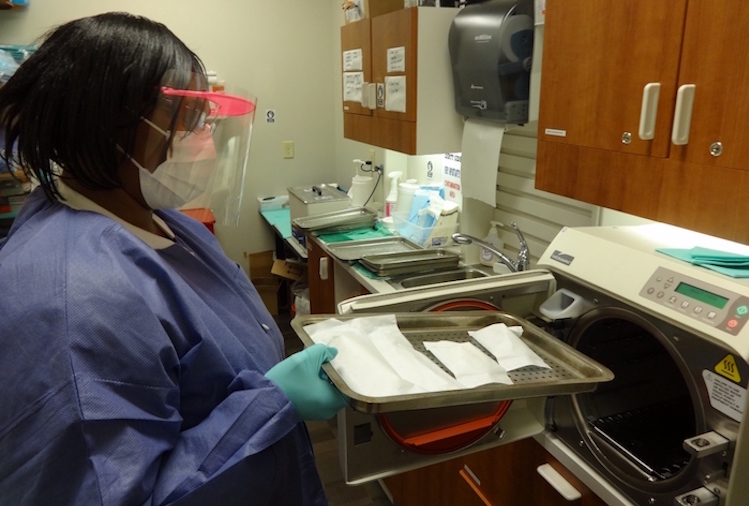 Dental assistant Lisha Spearman removes sterilized dental equipment from the autoclave at FHC Dental