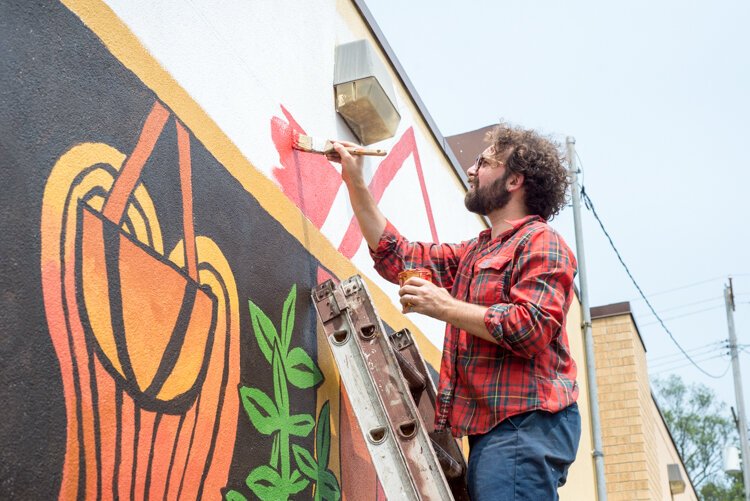 Trevor Grabill puts the finishing touches on his Vine neighborhood mural, which was started on the summer solstice and finished in early July.
