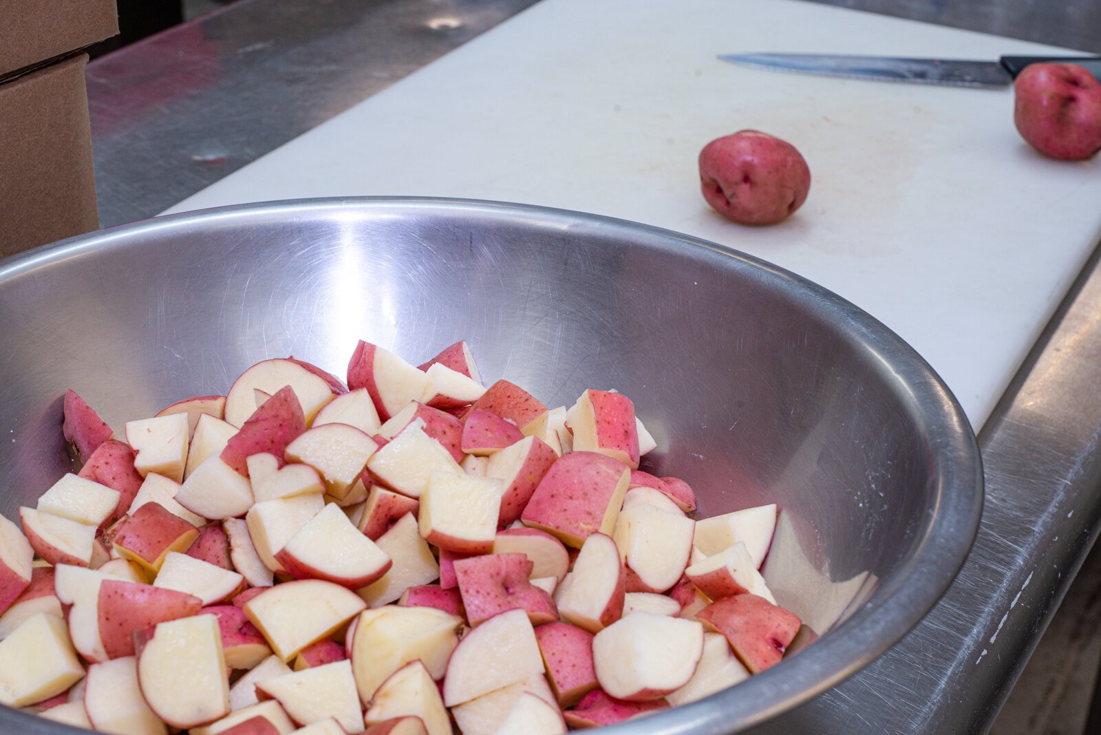 Derick Waters and Nina Martinez are slicing red potatoes for potato sala and suggesting  red potatoes for potato salad for customers of the Dirty Vegan.