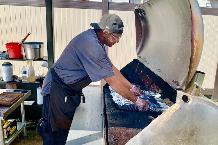 Ricky Thrash, who says he has been cooking for more than 45 years, keeps slabs of spare ribs warm on the grill behind Bone Yard Café.