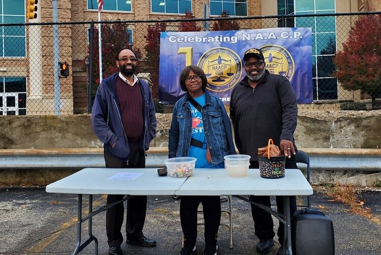 Carey Whitfield, President of the Battle Creek Branch of the NAACP, at left; Loraine Hunter, First Vice President, center; and Sam Gray, Second Vice President, stand at a table where they passed out Halloween treats during the KIDZ Day event.