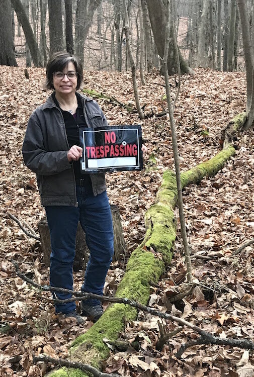 Heather Ratliff, vice president of the Stewards of Kleinstuck, removes one of the last "no Trespassing" signs from the 11.8-acre property being purchased by the organization.