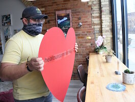 Tristan Bredehoft of Café Rica puts up a racial healing heart in the café’s front window.