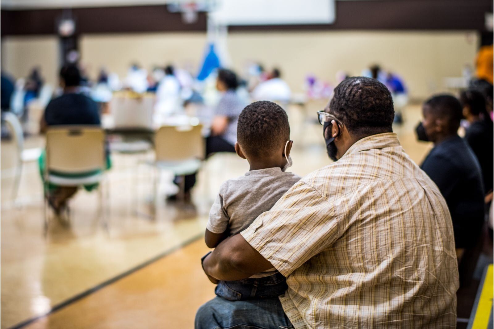 A man holds a little boy as they listen to plans for an affordable senior housing complex on July 21, 2022 at Mt. Zion Baptist Church.
