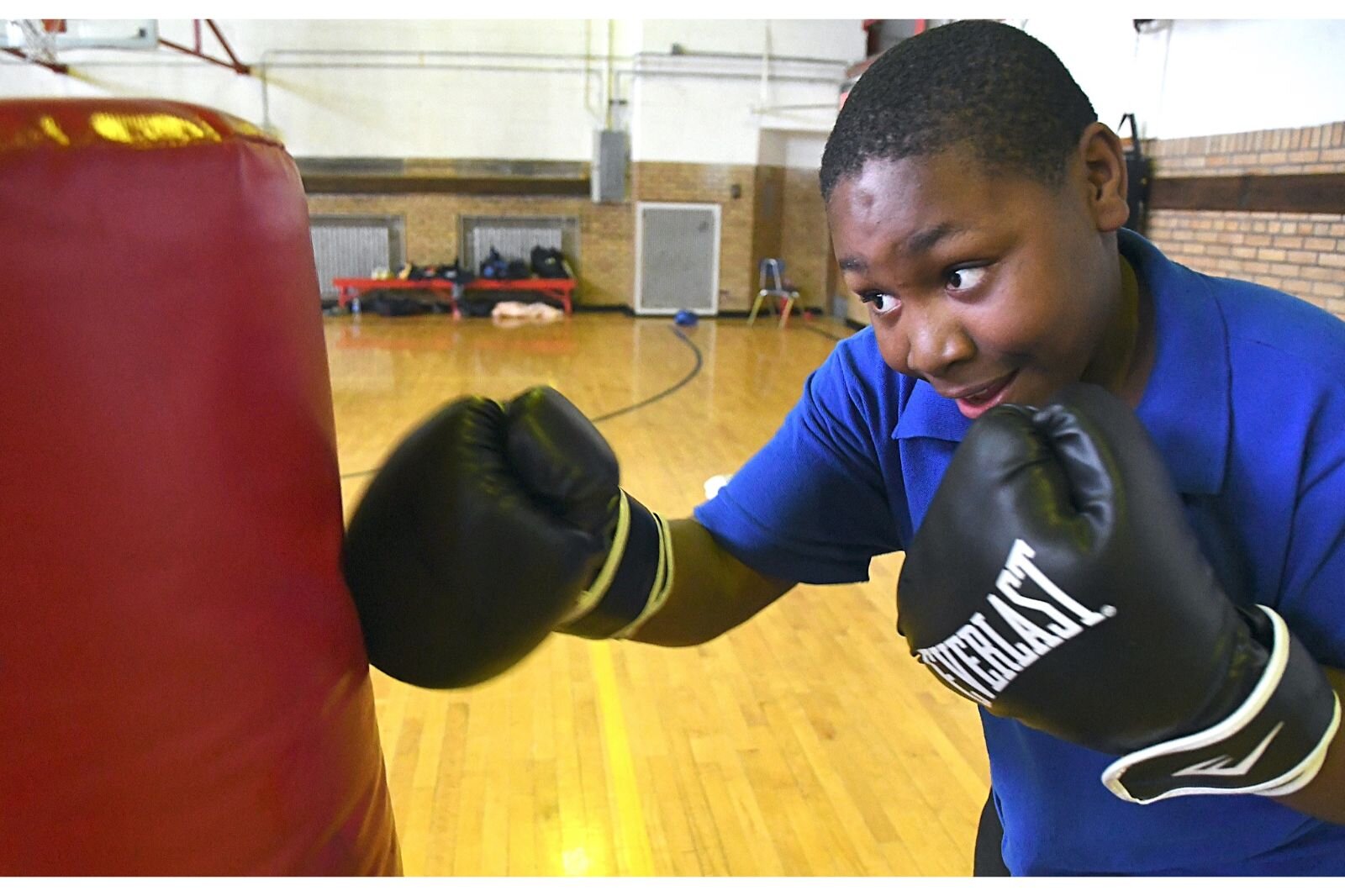 Marshaun Caldwell, wearing boxing gloves, punches a bag during a Cool People after-school session at Kingdom Builders.