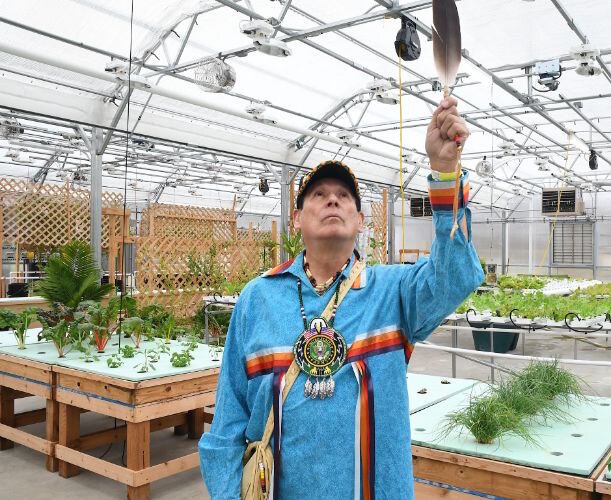 Doug Taylor, Historic Preservation Officer, lifts an eagle feather inside the greenhouse at the reservation.