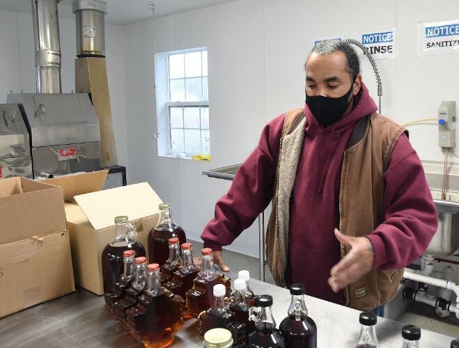 Robert Williams, Environmental Technician, points out some of the maple syrup produced in the sugar shack at the Pine Creek Indian Reservation.