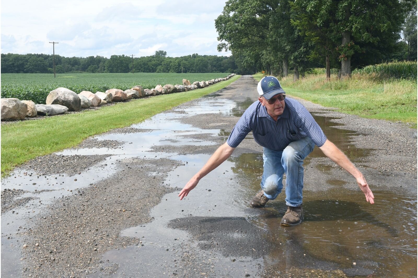Fred Heaton displays the size of potholes in a stretch of 24 Mile Road in Clarendon Township.