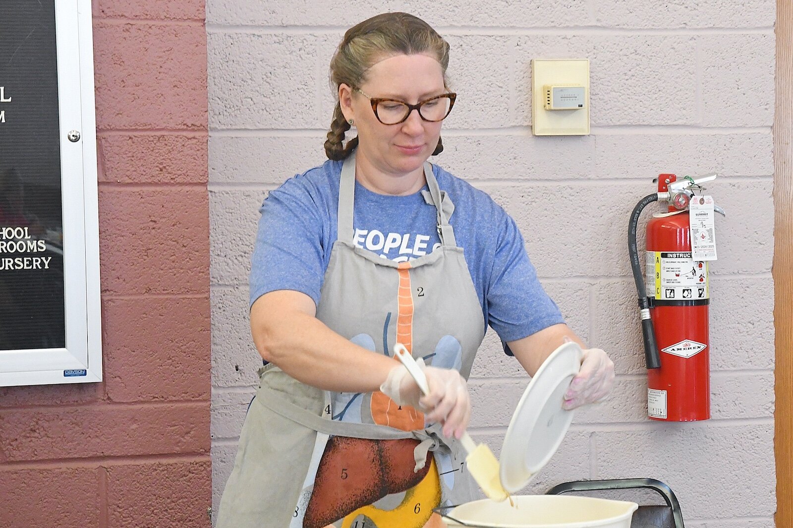 Rotary volunteer Jill Anderson scraps food from plates at St. Thomas Episcopal Church’s breakfast program.