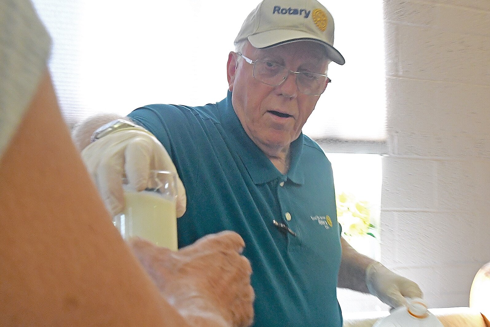 Rotary volunteer George Bratcher serves a glass of milk to a customer at St. Thomas Episcopal Church’s breakfast program.