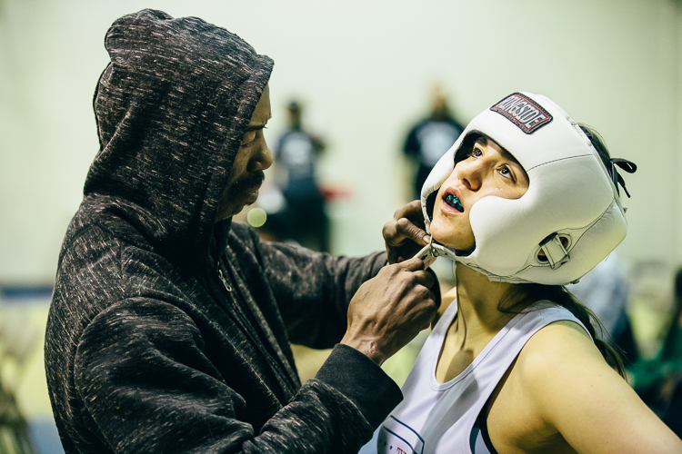 Maria Mazurieta, a University of Michigan student from A-Squared Fight Club, gets her headgear adjusted before the fight.