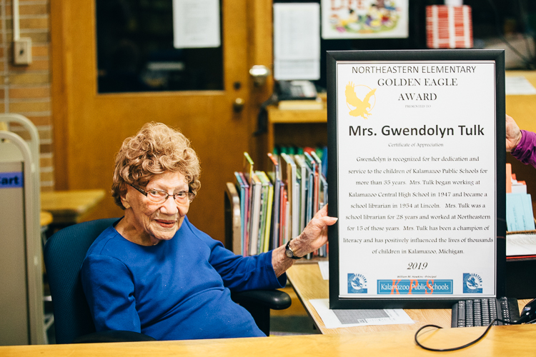 Former Northeastern Junior High School Librarian Gwen Tulk, who just turned 102, was honored at a special ceremony in her old library in April. Here she sits at her former librarian desk.