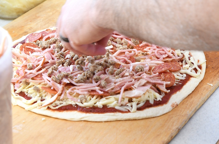 Jordan Wygant prepares a meat pizza at Pizza Sam’s.