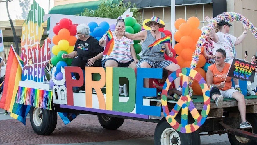 Participants sit on a float and wave to the crowd during 2017 Pride Month festivities in Battle Creek.