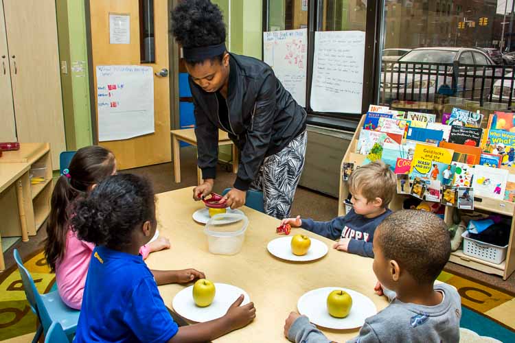 Nina Smith and children in the YWCA Children's Center eat an apple for a snack. Photo by Susan Andress