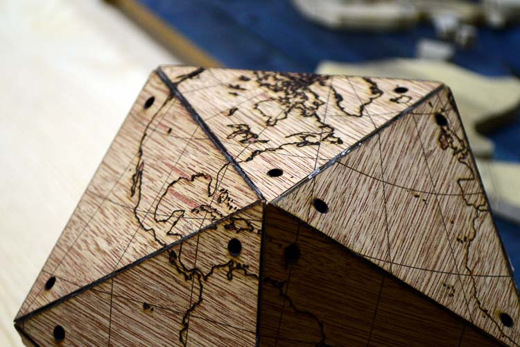 Polygonal ”globe” of laser-etched wood.