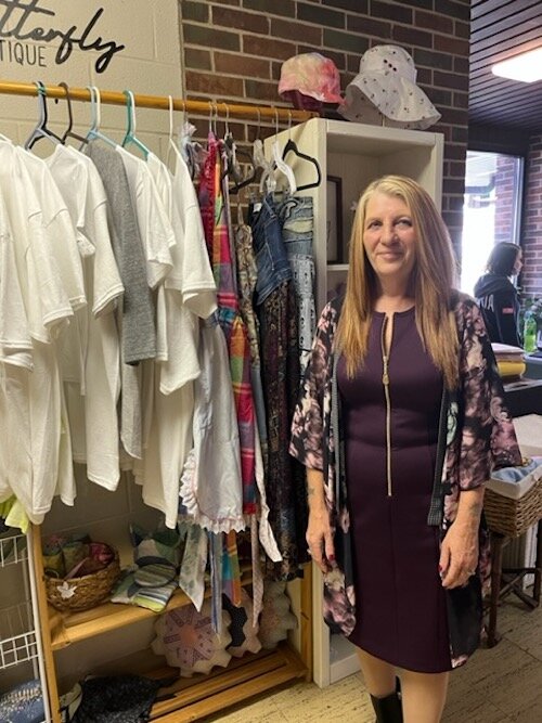 Teresa Momenee-Young, Executive Director of the Co-op, near the organization's Butterfly Closet stocked with hand-sewn items made by Co-op members available for purchase.