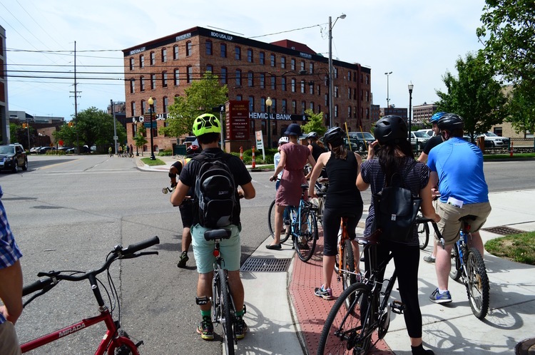 Crossing Kalamazoo Avenue on Pitcher Street: Where should a cyclist wait for the light to change? On the road, or on the sidewalk?