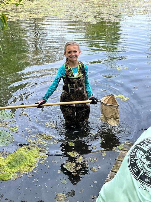 Kylie Dobbs, a former 5th-grade student in Nikki DeGowske’s class collects samples from the pond at their outdoor classroom. 