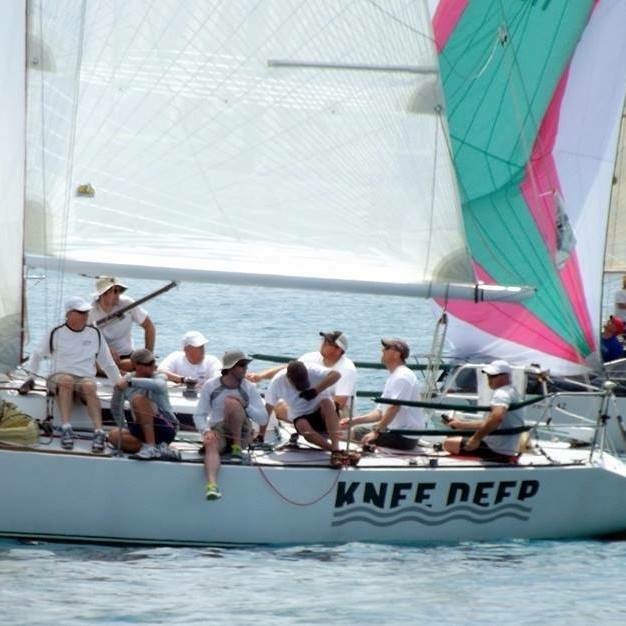 The crew on Knee Deep adjusts the sails.