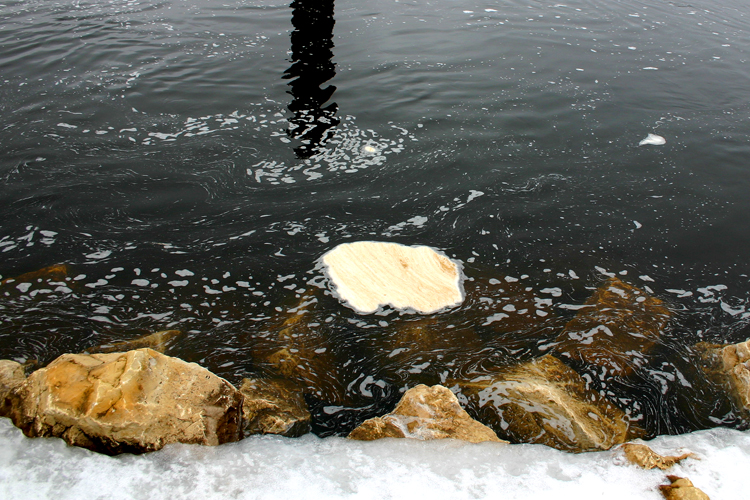 Rocks show themselves after a winter of being encased in Manistique River ice. 