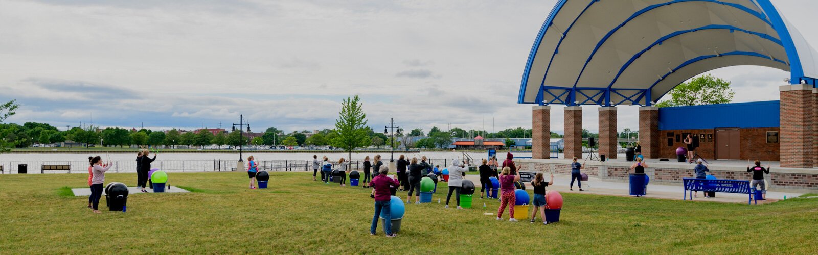 A group of exercises use the grassy lawn in front of the Wenonah Park Bandshell.