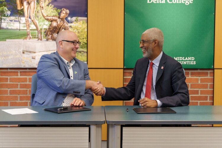 Michael Gavin, Delta College President, and George Grant Jr., Saginaw Valley State University President, shake hands after signing a new partnership agreement.